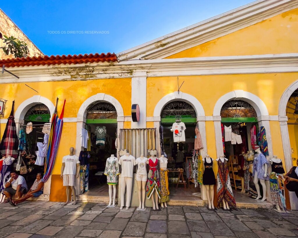 Prédio amarelo com arcadas e lojas de roupas e artesanato no Centro Histórico de São Luís