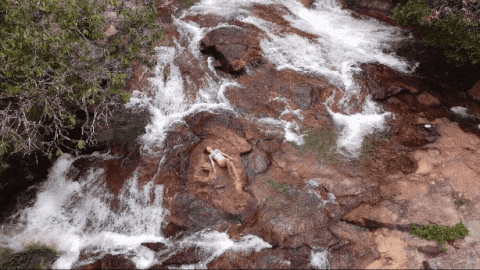 Luanne deitada nas pedras de uma cachoeira, vista de drone, no Munim